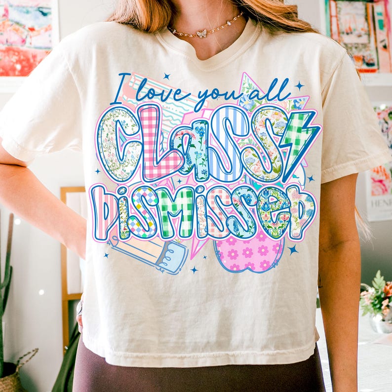 May include: A white t-shirt with a colorful graphic that says "I love you all Class Dismissed". The graphic is made up of different patterns, including floral, plaid, and stripes.