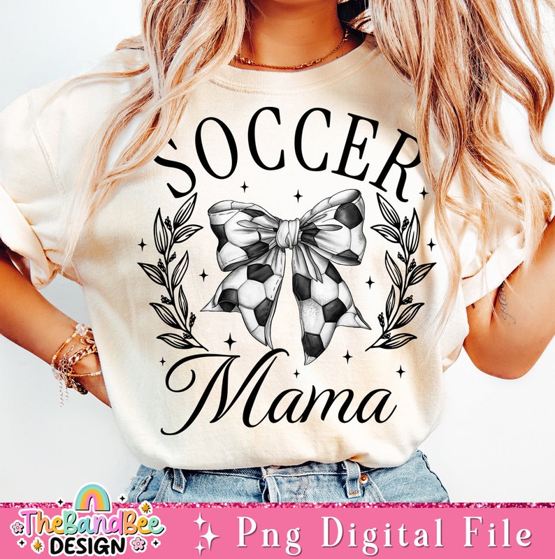 May include: A white t-shirt with a black graphic design that says "Soccer Mama" with a soccer ball bow and leaves.