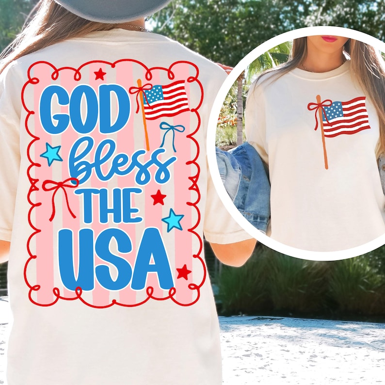 Puede incluir: Camiseta color crema con la bandera estadounidense y el texto "GOD bless THE USA" en azul. El dise&ntilde;o incluye estrellas rojas y un fondo a rayas rosas y blancas. Una versi&oacute;n m&aacute;s peque&ntilde;a de la bandera tambi&eacute;n est&aacute; en la parte delantera.