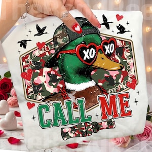 May include: White pillow with a graphic of a mallard duck wearing a camouflage hat and heart-shaped sunglasses with "XO" on the lenses. The pillow has the words "CALL ME" in green and red.