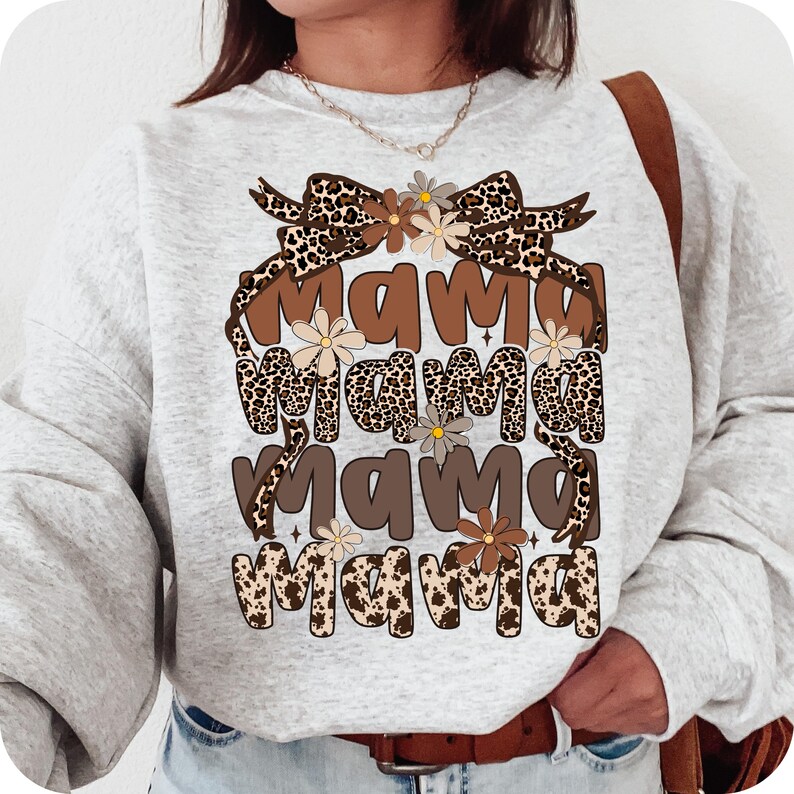 May include: A gray sweatshirt with a brown and black leopard print design. The design features the word "mama" repeated four times with a brown bow and flowers.