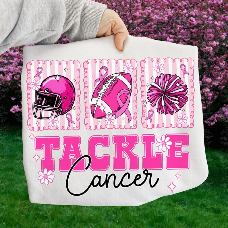 May include: White fabric with pink graphics of a football helmet, football, and pom-pom, each with a pink ribbon. The words "TACKLE Cancer" are in pink, with a black cursive "Cancer" below. The design is on a white background.