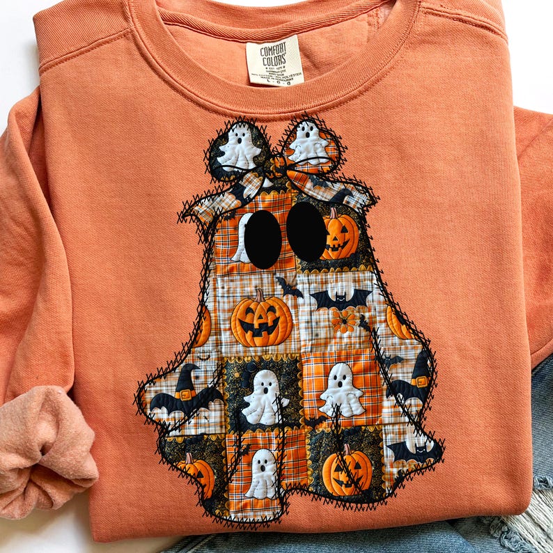 May include: Orange Comfort Colors sweatshirt with a patchwork ghost design. The ghost features pumpkins, bats, and ghost figures. The design is stitched with black thread, creating a unique Halloween-themed apparel.