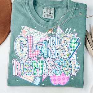 May include: A teal green t-shirt with the text "I love you all Classy Dismissed" in a colorful patchwork style. The text is surrounded by stars and a lightning bolt.