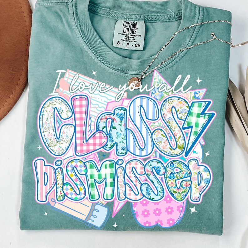 May include: A teal green t-shirt with the text "I love you all Classy Dismissed" in a colorful patchwork style. The text is surrounded by stars and a lightning bolt.