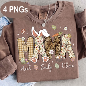 Puede incluir: Una sudadera marrón con la palabra "MAMA" en una mezcla de patrones y diseños, incluyendo cuadros, flores y estampado de leopardo. La palabra "MAMA" tiene orejas de conejo encima. Los nombres "Noah", "Emily" y "Olivia" están debajo.