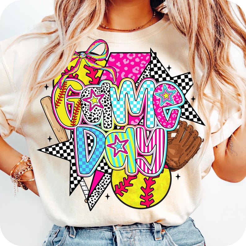 May include: A white t-shirt with a colorful graphic design that says "Game Day". The design features a baseball, a bat, a glove, and stars.