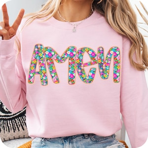 May include: Pink sweatshirt with the word "AMEN" in large, colorful letters made of floral patterns.