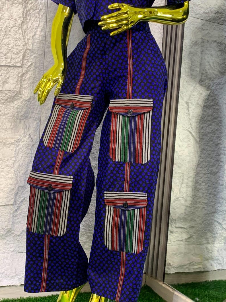 May include: Blue patterned pants with vertical red stripes and striped pockets. The pockets feature red, green, and white stripes. The pants are part of a matching set.