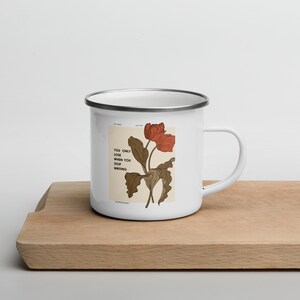 May include: White enamel mug with a silver rim and a floral design. The mug has the text "You only lose when you stop writing" printed on it.