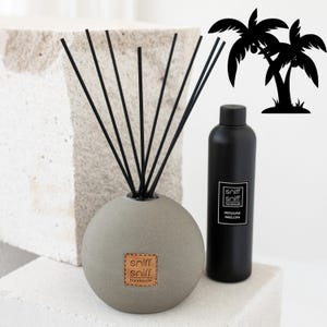 May include: A gray, round diffuser with black reeds and a brown label that says "sniff sniff handmade". The diffuser is next to a black bottle with a white label that says "sniff sniff handmade REGGAE MELON".