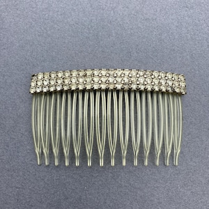 May include: A silver hair comb with a row of clear rhinestones.