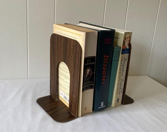 May include: A set of brown wooden bookends holding up a stack of books. The books have titles like "Diseases" and "Benjamin Franklin".