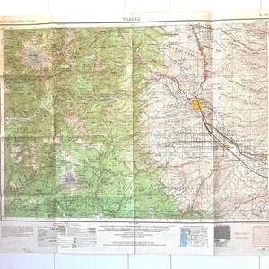 May include: A vintage map of Yakima, Washington, showing topographical features, roads, and railroads. The map is printed on paper and has a yellowed appearance. The map is titled "Yakima" in the upper center.