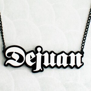 May include: A black chain necklace with a white nameplate pendant that reads "Dejuan" in a bold, gothic font.