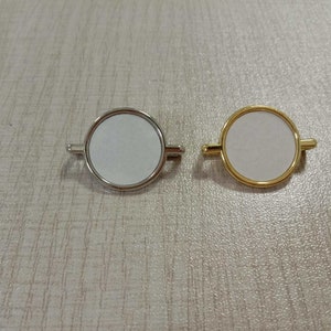 May include: Two round blank photo frames with metal edges. One frame is silver and the other is gold.