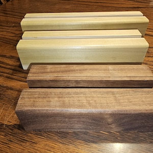 May include: Three wooden blocks, two are light brown and one is dark brown. The blocks are stacked on top of each other.