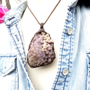 May include: A purple and white agate pendant with a brown leather cord necklace. The agate is a cluster of small, round nodules.