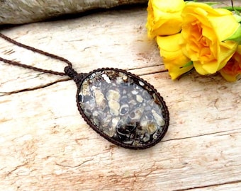 May include: A brown cord necklace with a large oval pendant featuring a unique, marbled pattern in shades of brown, white, and black.