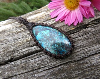 May include: A teal blue gemstone pendant with brown leather cord. The pendant is in the shape of a teardrop and has a marbled pattern.