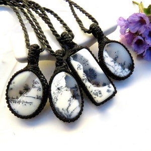 May include: Five necklaces with black cords and pendants made of white and grey dendritic agate. The pendants are in various shapes, including oval and rectangular.