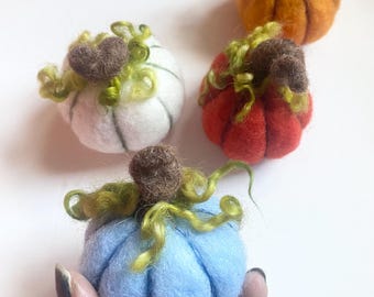 May include: Four felt pumpkins in different colors: orange, white, red, and blue. Each pumpkin has a green felt stem and curly green felt leaves.