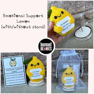 Peut inclure: Un citron crocheté avec un visage heureux tenant une pancarte qui dit "Go squeeze the day! You got this!" Le citron est assis sur un petit support en bois. Le citron est de couleur jaune et le panneau est blanc avec du texte noir. Le citron est un citron de soutien émotionnel.