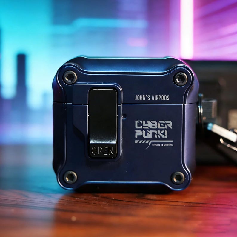 May include: A navy blue Airpods case with the text "JOHN'S AIRPODS" and "CYBER PUNK!" printed on the front. The case has a rectangular shape with rounded corners and visible screws. The word "OPEN" is printed on the front.