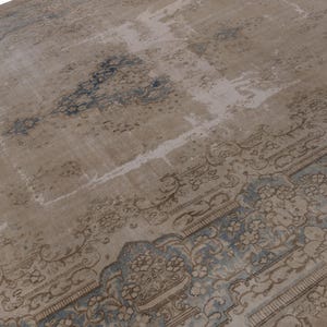 May include: A vintage rug with a faded, light brown background and a blue and brown patterned border. The rug has a distressed look and is made of wool.