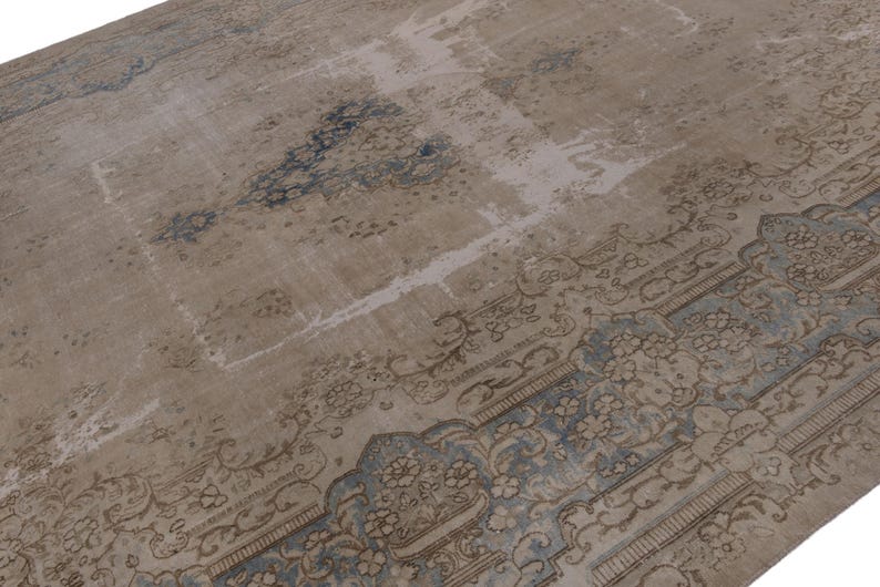 May include: A vintage rug with a faded, light brown background and a blue and brown patterned border. The rug has a distressed look and is made of wool.
