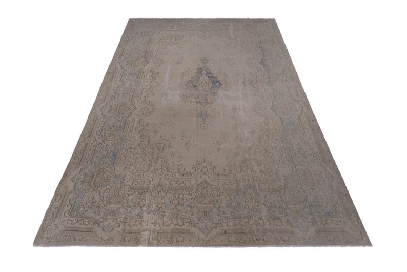 May include: A vintage rug with a faded floral pattern in shades of beige and blue. The rug has a worn and distressed look, giving it a rustic and antique feel.