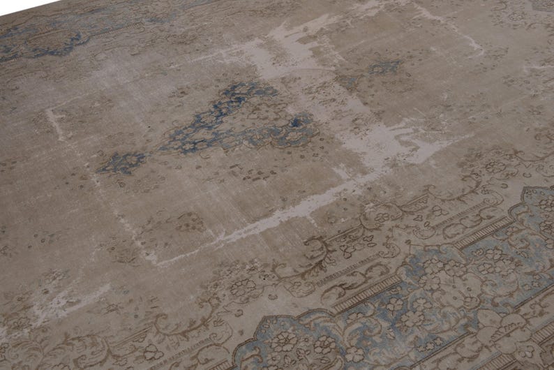 May include: A vintage rug with a faded, light brown background and a blue and brown floral pattern. The rug has a distressed look with some areas of wear and tear.