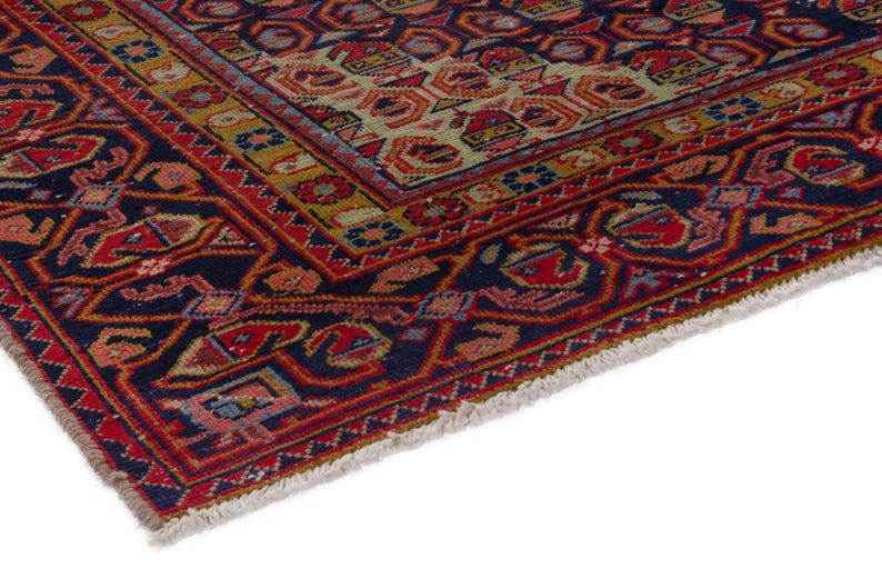 May include: Close-up of a section of a Persian rug with a detailed geometric pattern. The rug features a navy blue border with red and orange accents. The central design includes a mix of red, orange, and beige shapes.