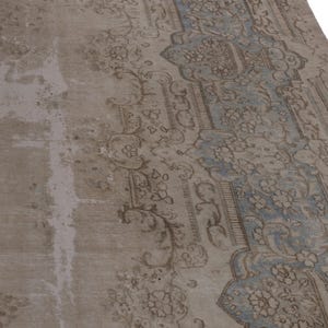 May include: A vintage rug with a faded blue and brown floral pattern. The rug has a worn and distressed look, giving it a unique character.