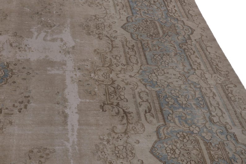 May include: A vintage rug with a faded blue and brown floral pattern. The rug has a worn and distressed look, giving it a unique character.