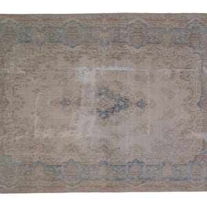 May include: A vintage rug with a faded beige background and a blue and beige patterned border. The rug has a worn and distressed look, giving it a rustic and antique feel.