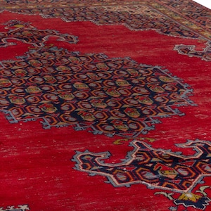May include: A vibrant red area rug with intricate geometric patterns in navy blue, gold, and light blue. The rug features a central medallion design and detailed borders, showcasing a traditional aesthetic. The rug's texture appears slightly distressed.
