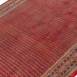 Puede incluir: Una alfombra roja estampada con un borde detallado. La alfombra tiene un patr&oacute;n floral repetido en un color rojo m&aacute;s oscuro. El borde presenta un dise&ntilde;o complejo con tonos de azul, beige y rojo. La alfombra es rectangular.