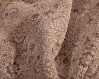 May include: A close-up of a beige rug with a subtle pattern. The rug is made of a soft, woven material and has a slightly distressed look.