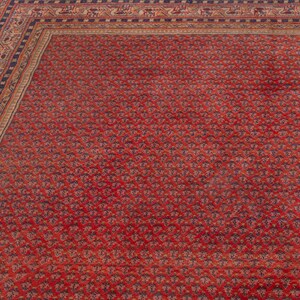 Puede incluir: Primer plano de una alfombra oriental roja con un patr&oacute;n floral repetido. La alfombra tiene un borde azul oscuro y beige con dise&ntilde;os detallados. El campo principal de la alfombra es de color rojo intenso.
