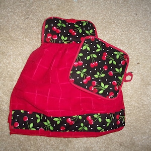 May include: Red kitchen towel with a black and white cherry print border and a matching cherry print pot holder.