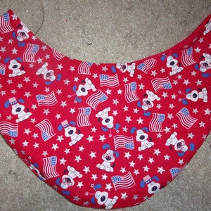 May include: Red fabric with a white and blue pattern of stars, American flags, and cartoon dogs wearing hats.