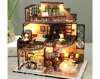 May include: A miniature dollhouse with a brown wooden exterior and a white base. The dollhouse has multiple levels and rooms, including a kitchen, living room, bedroom, and balcony. The dollhouse is lit with small lights and features miniature furniture and decor.
