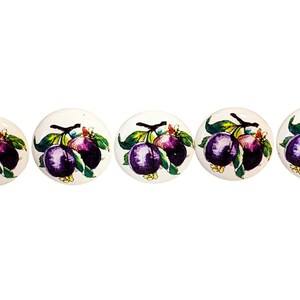 May include: Five round white ceramic knobs, each featuring a hand-painted illustration of two dark purple plums on a brown branch with green leaves. The fruit design is consistent across all five pieces, showcasing a glossy finish and smooth surface.