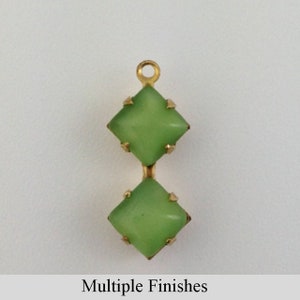 May include: Two green glass square-shaped rhinestones with gold settings, connected by a gold loop. The rhinestones have a slightly frosted finish.