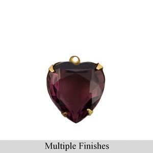 May include: A faceted, heart-shaped pendant in deep purple, set in a gold-colored metal frame. The pendant has a small loop at the top for hanging. The text "Multiple Finishes" is displayed below the pendant.