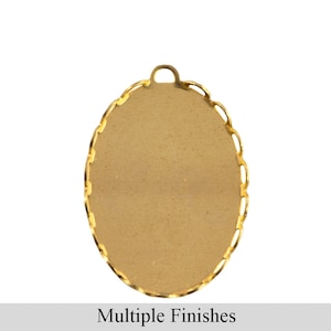 May include: A gold-colored oval pendant base with a scalloped edge and a small loop at the top. The base has a flat surface for adding a design. The text "Multiple Finishes" is at the bottom.