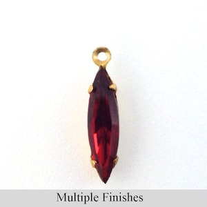 Puede incluir: Un colgante de cristal rojo en forma de marquesa con un engaste dorado y un bucle para sujetarlo a una cadena o cordón.