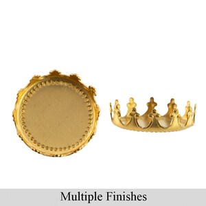 May include: Gold-toned metal crown-shaped bezel setting for jewelry making. The bezel is round and has a smooth, flat surface. It is shown in two views: one with the bezel facing the camera and the other with the bezel turned sideways.