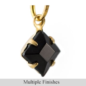May include: A black, square-cut gemstone pendant with a gold-coloured setting. The pendant is suspended from a gold-coloured loop. The text "Multiple Finishes" is displayed at the bottom of the image.